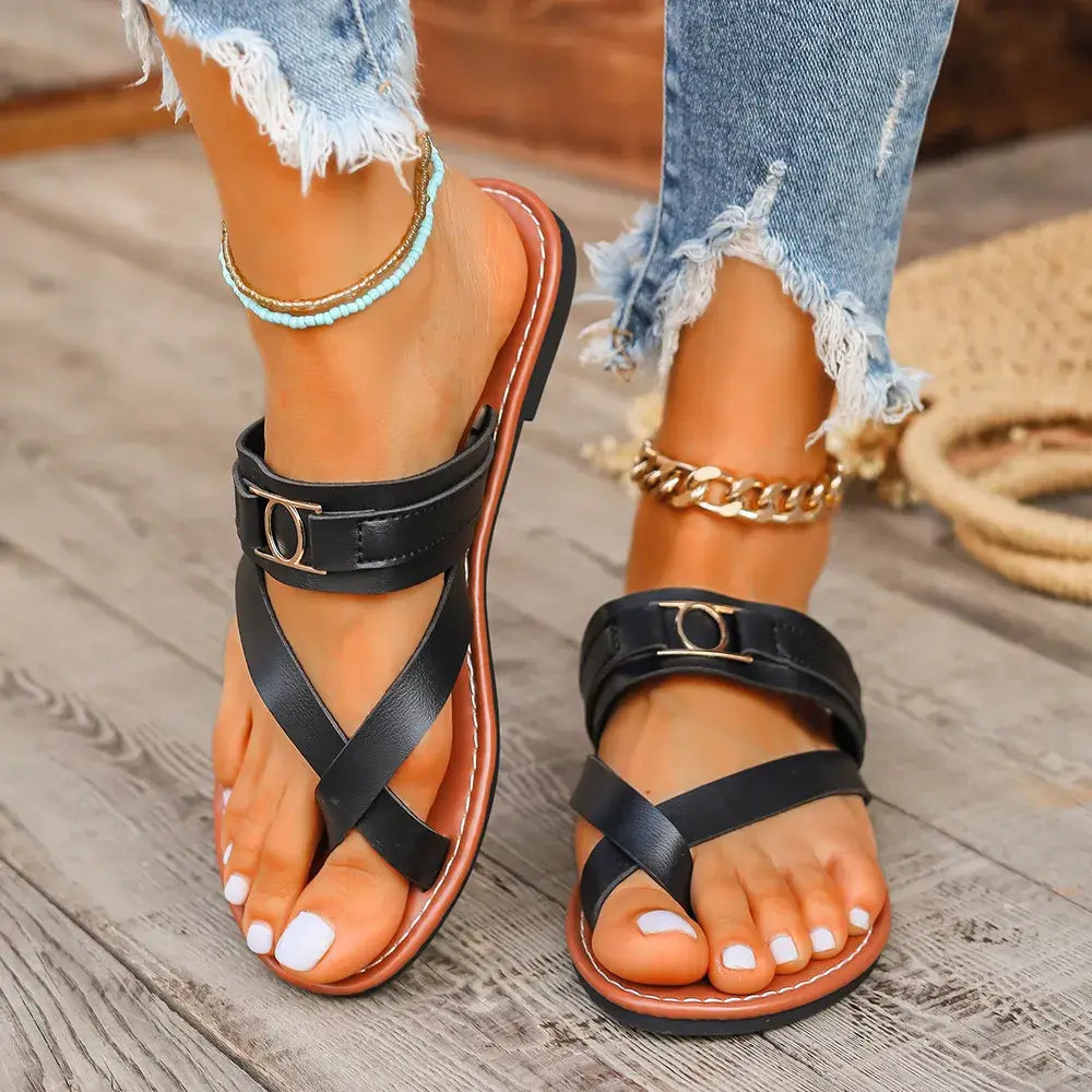 Toe Loop Flats Sandals showcased in black, featuring a stylish toe loop design, set against a wooden floor.